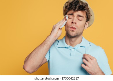 Sweaty Man Wiping Face With Napkin Isolated On Yellow