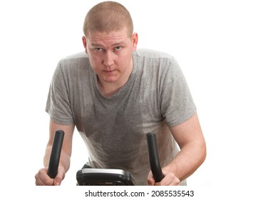 A Sweaty Man Working Out On An Exercise Bike On A White Background. 