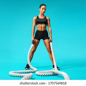 Sweaty Woman Resting After Working Out With Ropes. Photo Of Sporty Woman On Turquoise Background. Strength And Motivation. Full Length