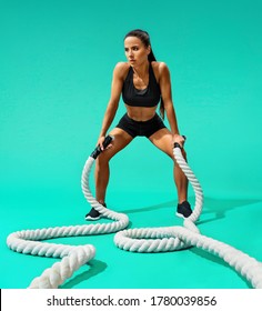 Sweaty Woman Resting After Working Out With Ropes. Photo Of Sporty Woman On Turquoise Background. Strength And Motivation. Full Length