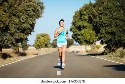 Sweaty Woman Running On Rural Road. Hispanic Female Athlete Training And Exercising Hard For Intense Marathon.