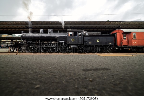 Göteborg, Sweden - Aug 08, 2021: Side view\
of an old SJ class E2 steam locomotive stands at the railway\
station in Gothenburg ready for departure. The train is run by a\
local railway\
association.