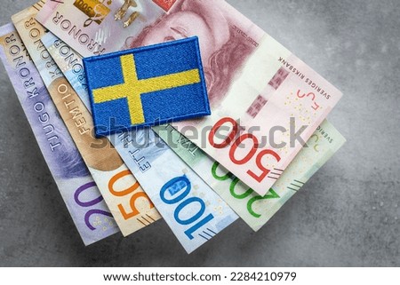 Sweden flag lying on a bundle of swedish kronas, Currency of Sweden, business and financial concept