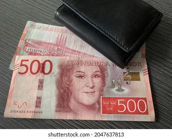 Sweden krone bills with black leather wallet isolated on dark wood background. Swedish krona money - 500 fem hundra kronor. 