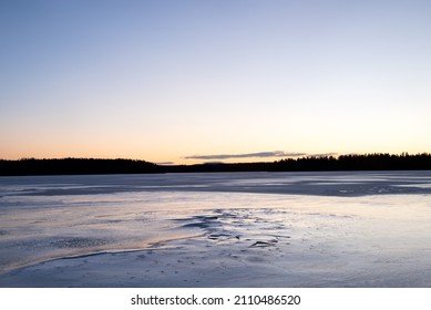 Sweden, Ljusnaren - The frozen surface of a forest lake at blue hour on a crisp winter day