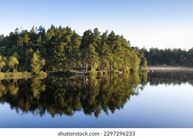Swedish archipelago landscape with sun flooded forest mirrored in a lake