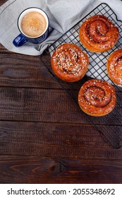 Swedish cinnamon buns Kanelbulle with cup of coffee, wooden background, vertical, copy space