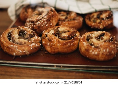 Swedish Cinnamon Buns On A Tray With A Kitchen Towel Covering Some Of Them