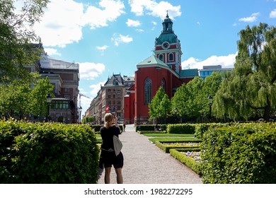 Swedish Domestic Tourist Taking Picture Of A Red Church By Kungsträdgården (the Royal Garden) In Stockholm On A Sunny Summer Day