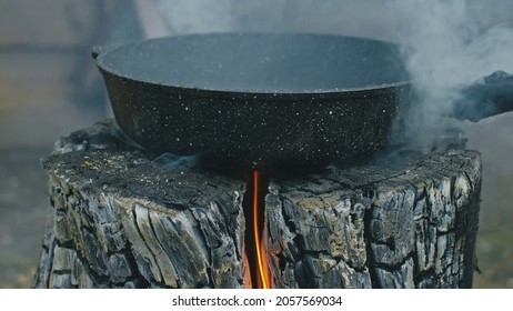 Swedish or finnish log candle. Fire burning from inside the wooden log at day. Cooking on a fire. Fry sunflower seeds in a pan.