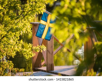 Swedish Flag On A Floating Dock In Summer Sunset Light In Sweden.