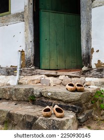 Swedish Hasbeens wooden shoes on old stairs by a farmhouse green door. Hard, timbered clog shoe or protective footwear made of wood by the entrance of a countryside house. Antique Swedish fashion - Shutterstock ID 2250930145