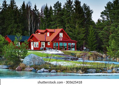 Swedish Landscape With Green Fir Tree Forest And Red  Typical House On The Coast Of Sea Bay