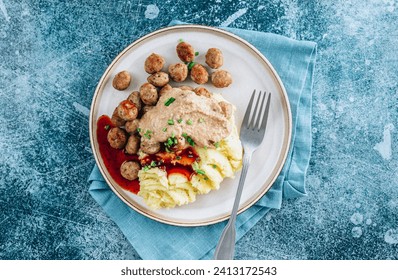 Swedish meatballs kottbullar, mashed potato, onion sauce and lingonberry sauce. Blue stone background. Top view with copy space