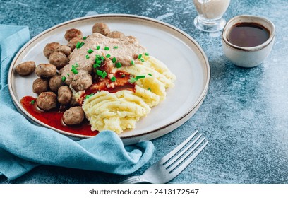 Swedish meatballs kottbullar, mashed potato, onion sauce and lingonberry sauce. Blue stone background. Selective focus