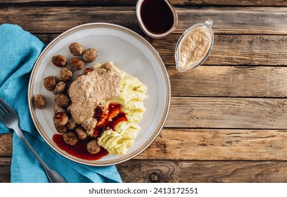 Swedish meatballs kottbullar, mashed potato, onion sauce and lingonberry sauce. Wooden background. Top view with copy space
