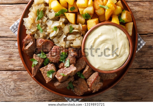 Swedish recipe\
pyttipanna for beef rydberg with stewed onions and fried potatoes\
with mustard sauce close-up on a plate on the table. horizontal top\
view from above\
