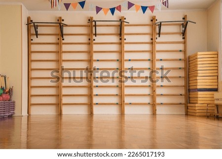 Swedish wall with wooden ladder mounted in school gym. Interior of sport class room of college or gymnasium.