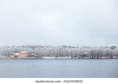 Swedish white winter snow landscape over calm water with Nedre Manilla orange villa on Djurgården, Stockholm, by the waterfront - Powered by Shutterstock