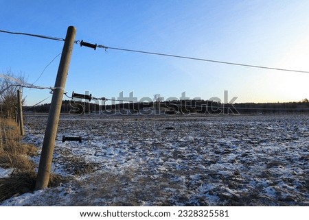 Swedish winter day. Leaning fence at the countryside. Sunset. Sparse with snow. Sigtuna, Sweden.