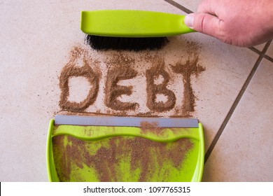 Sweep debt clean concept with debt written in dirt on a floor and a person is about to sweep the debt dirt in a dust pan using a small hand broom