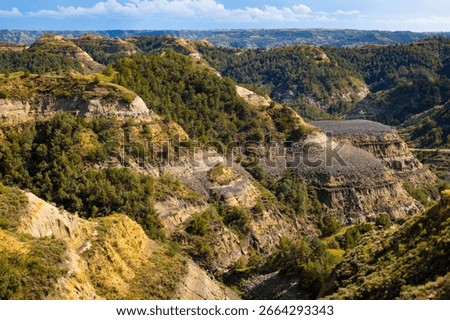 A sweeping panoramic view captures the dramatic landscapes along the Caprock Coulee Trail at Theodore Roosevelt National Park