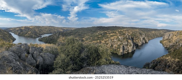 A sweeping view of a river winding through a rugged canyon beneath a dynamic sky.