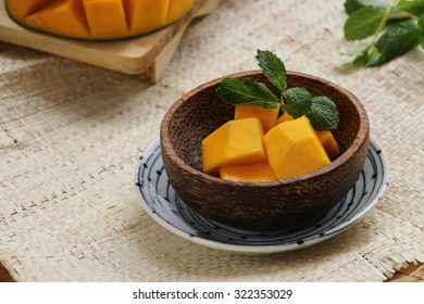 Sweer Aromatic Mango Cut Into Cubes, Placed Into A Bowl Made From Coconut Husk And Underlined With A Ceramic Plate.