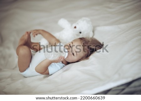 Sweet Adorable Child Lying Down in His Bed with His Best Friend, Soft Toy Teddy Bear and Eating Formula. Preparing To Nap. Healthy Babies Life.