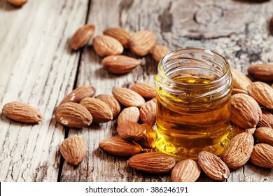 Sweet Almond Oil, First Extraction, In A Small Glass Jar, Dry Almond Nuts On An Old Wooden Background, Selective Focus