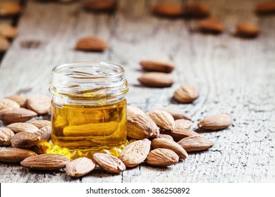 Sweet Almond Oil, First Extraction, In A Small Glass Jar, Dry Almond Nuts On An Old Wooden Background, Selective Focus