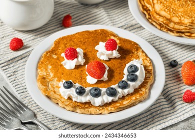 Sweet American Smiley Face Breakfast Pancakes with Whipped Cream and Berries