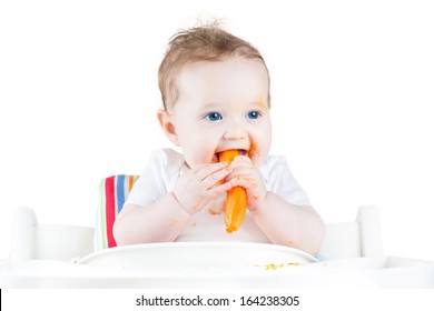 Sweet Baby Eating Her First Solid Food In A White Chair, Isolated On White