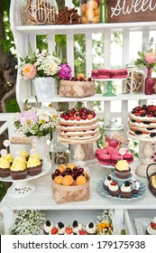 Sweet bar on summer wedding. Layer cakes with protein cream and fresh cherry and berries on a cake stand outdoors