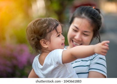 Sweet Beautiful Baby Girl With Hug Of Mother And Playing. Happy Loving Family Kissing And Hugging.