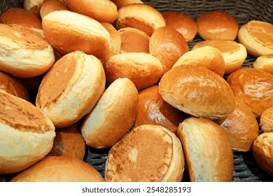 Sweet burger buns background. Fresh rolls stacked on a store shelf. Group of classic bread rolls on display. Bakery section with a pile of golden brown buns. Perfect for sandwiches or breakfast. 