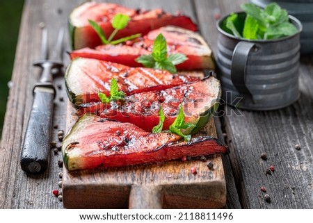 Sweet burned watermelon with red pepper and mint. Grilled watermelon on grill with flames.