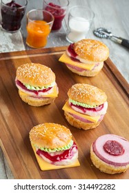 Sweet cake in the form of a burger, strawberry mousse with white chocolate and roll with sesame seeds, cooking background