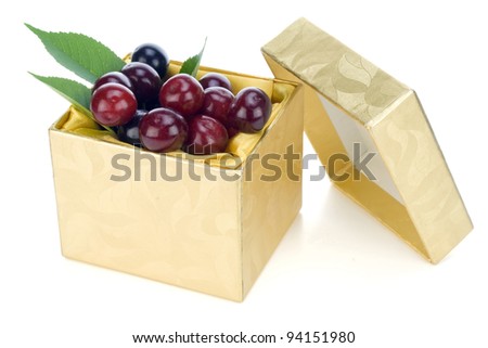 Sweet cherries lies in a small gold mass production  box macro. Selective focus