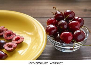 Sweet Cherry On A Yellow Plate On A Wooden Table With Small Glass Bowl Full With Cherries. Low Angle Shot