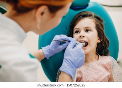 Sweet child doing a teeth examination by a professional specialist in a pediatric stomatology.