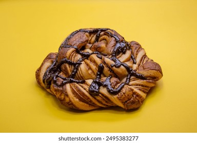 sweet chocolate bread in polygon shape with isolated chocolate topping on a yellow background 