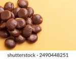 Sweet Chocolate Covered Caramel Disks on a Yellow Background