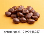 Sweet Chocolate Covered Caramel Disks on a Yellow Background