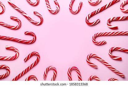 Sweet Christmas candy canes on pink background, flat lay. Space for text