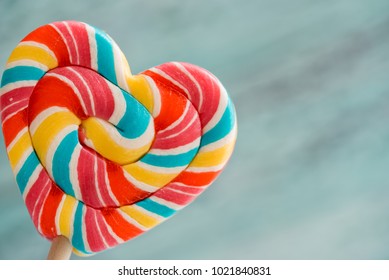 Sweet colored striped rainbow candy on a stick in the form of a heart. on a old vintage wooden background. The concept for Valentine's Day. Copy space. Place for your inscription - Powered by Shutterstock