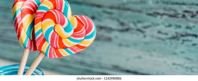 Sweet colored striped rainbow candy on a stick in the form of a heart. on a old vintage wooden background. The concept for Valentine's Day. Copy space. Place for your inscription - Powered by Shutterstock