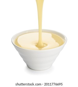 Sweet Condensed Milk Pouring Into Bowl On White Background