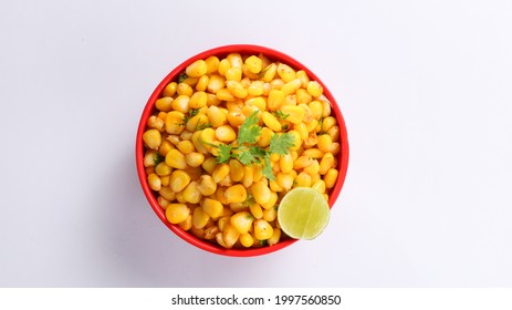 Sweet Corn Chat Or Steamed Yellow Sweet Corn, Chat Masala And Lemon, Served In Black Dish. Indian Chat Or Snack. Sweetcorn Or Sweet Corn On Isolated White Background. Top View