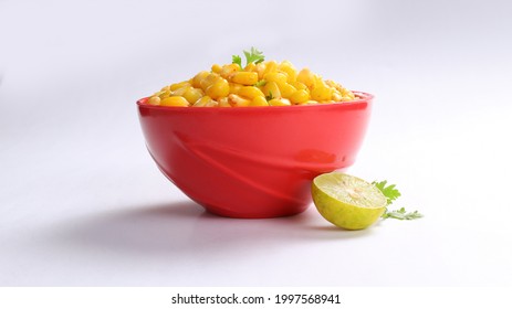 Sweet Corn Chat Or Steamed Yellow Sweet Corn, Chat Masala And Lemon, Served In Red Bowl. Indian Chat Or Snack. Sweetcorn Or Sweet Corn On Isolated White Background